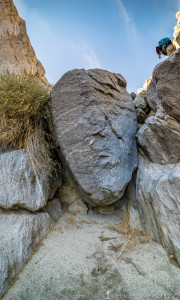 Another member of the hiking group making his way up and over on the right side of the large rock blocking the wash